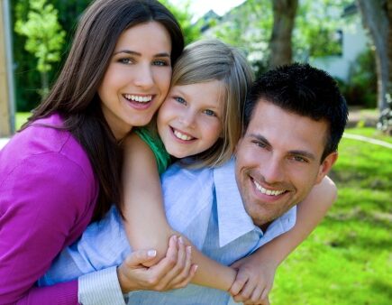 Couple giving young child piggyback rides smiling
